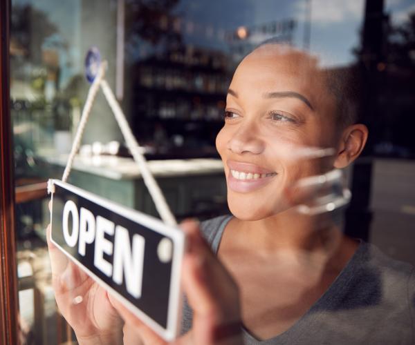 Businesswoman turning open sign on door of a shop