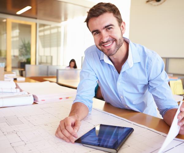 Architect with digital tablet studying plans in office