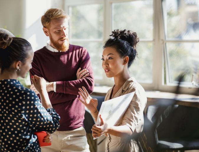 Colleagues standing in a small group discussing something.