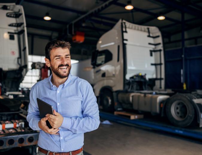 Worker with tablet with trucks in the background